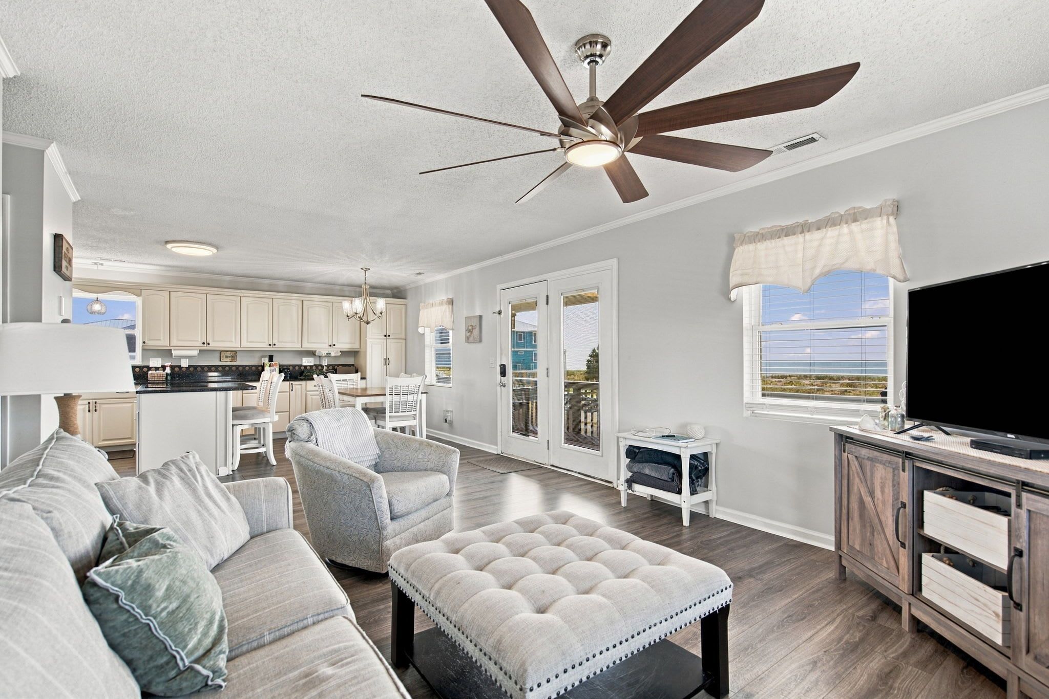 A spacious living room with a ceiling fan, a television, and a view of the outdoors.