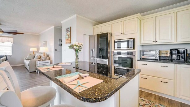 Een moderne keuken met een centraal kookeiland, ingebouwde apparatuur, en een zithoek met een bank en tafel.