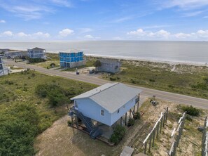 Une zone côtière avec une route, un bâtiment bleu doté d’un balcon et une construction plus petite.