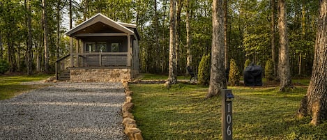 A cabin with a stone foundation and a wooden roof, surrounded by a forest.