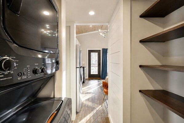 A modern kitchen with a built-in stove, a dining area with a wooden table, and a view into the living room.