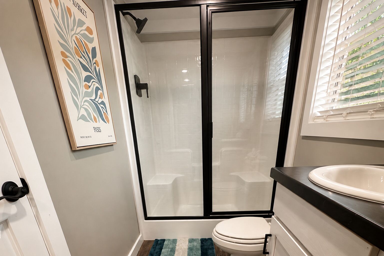 A bathroom with a glass-enclosed shower, a white toilet, and a sink with a black countertop.
