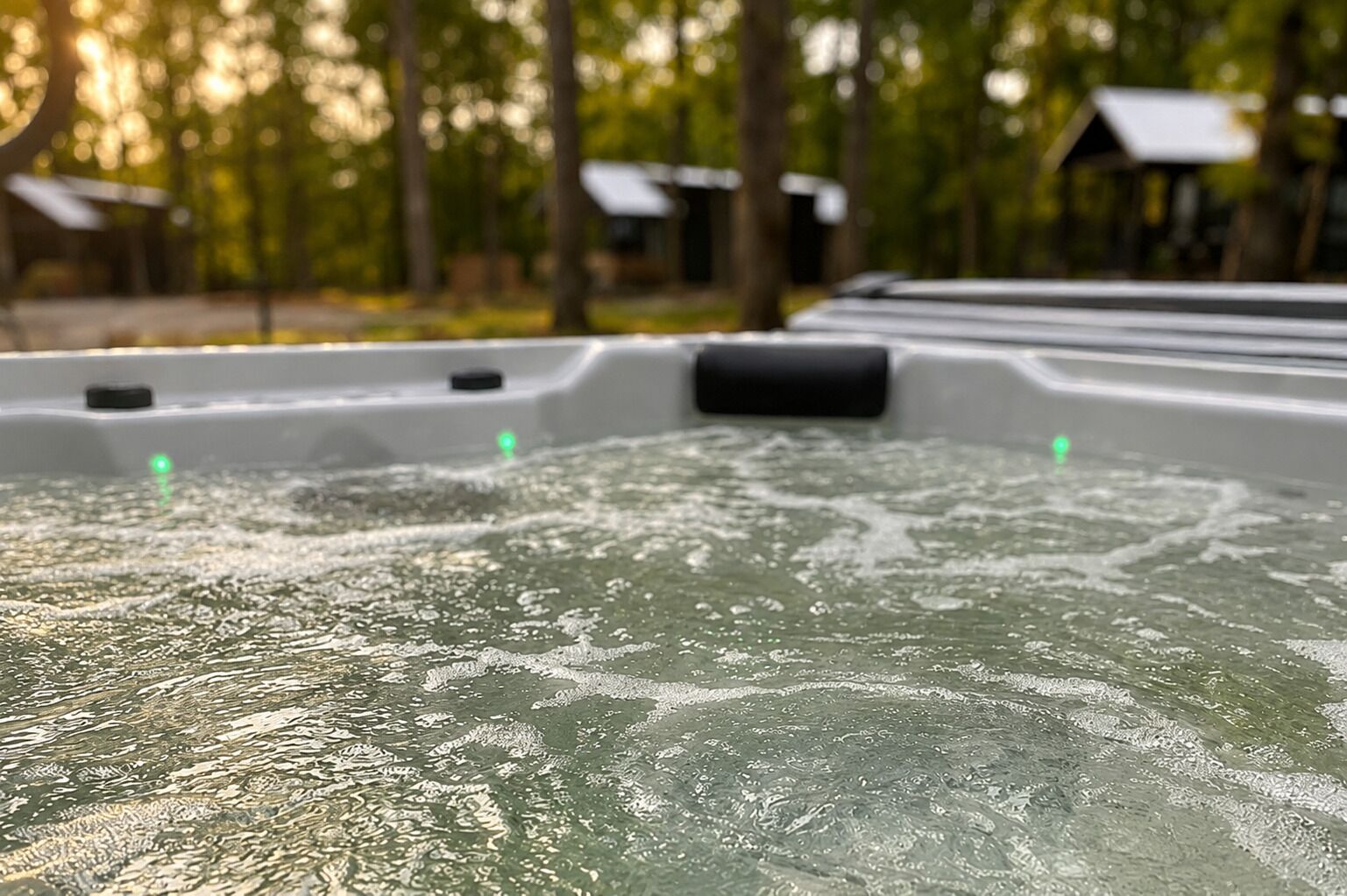 A hot tub with water jets, surrounded by trees and a building with a sloped roof.