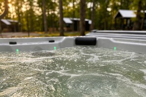 A hot tub with water jets, surrounded by trees and a building with a sloped roof.