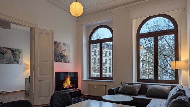 Una sala de estar moderna con chimenea, ventanas arqueadas amplias y un comedor.