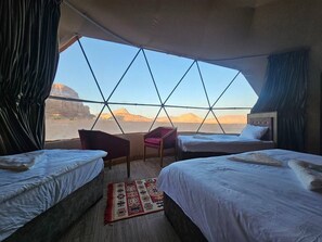 Une chambre avec deux lits, une chaise et une vue sur un paysage désertique.