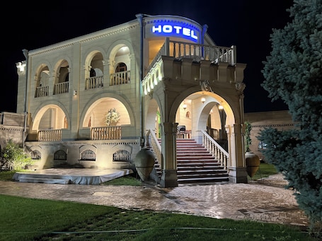 A hotel with a prominent "HOTEL" sign, a grand entrance with a staircase, and a well-lit facade.