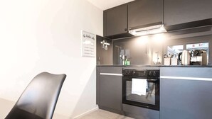 Una cocina moderna con horno empotrado, una silla negra y un cartel en la pared.
