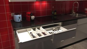 A modern kitchen with a built-in drawer organizer, a coffee maker, and a red-tiled backsplash. - Apartment with shower - washing machine - 180 degree lake view (Rorschach)