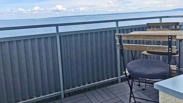 En balkon med udsigt over havet, et træbord og en stol.