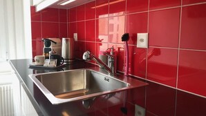 Eine moderne Küche mit Spüle aus Edelstahl, einer roten Fliesenrückwand und einer schwarzen Arbeitsplatte.