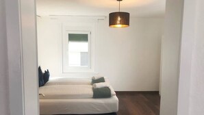 Ein Schlafzimmer mit Bett, Fenster und einer Pendelleuchte.