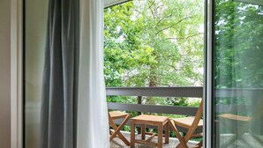 A room with a sliding glass door leading to an outdoor balcony with a wooden table and chairs.