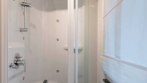 A modern shower enclosure with a glass door, a chrome showerhead, and a handheld shower attachment.
