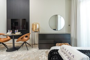 A modern bedroom with a bed, a round mirror, a dresser, a table with chairs, and a decorative lamp. - Nasma Holiday Homes - Azizi Riviera 6 (Dubai)