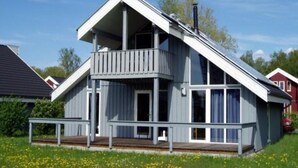 Ett tvåvåningshus med en balkong, en skorsten och en terrass.