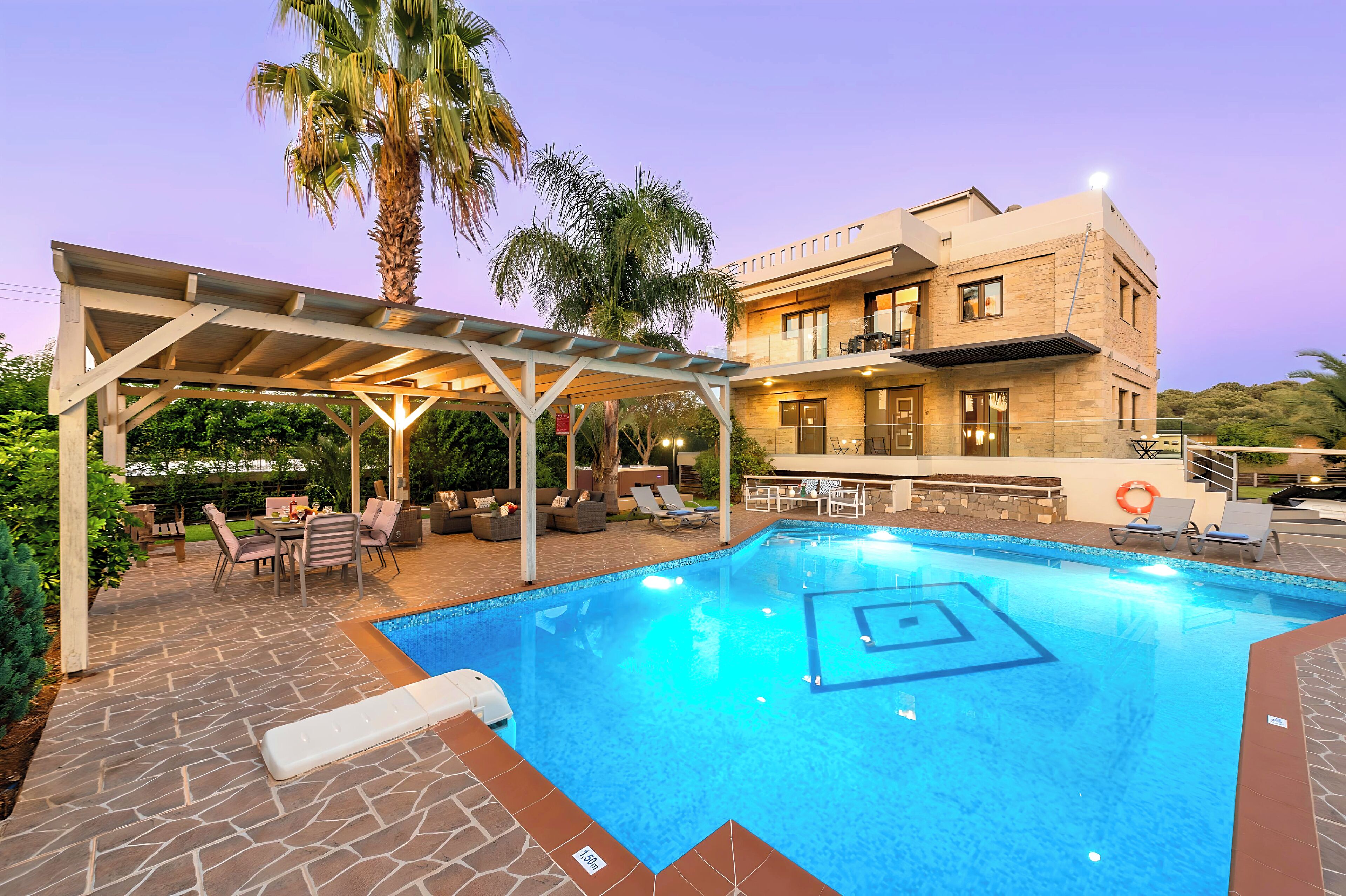 A swimming pool with a pergola, outdoor seating, and a building with a balcony.