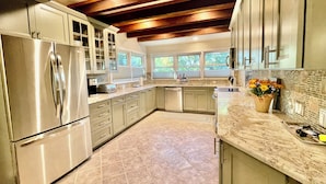 A modern kitchen with stainless steel appliances, a marble countertop, and a wooden ceiling. - Just minutes to the beach with a hot tub and fire pit! (Rehoboth Beach)