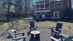 A backyard with a patio area featuring Adirondack chairs and a round table. - Just minutes to the beach with a hot tub and fire pit! (Rehoboth Beach)