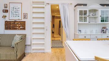 A cozy room with a striped sofa, a white cabinet with glass doors, and a wooden floor.