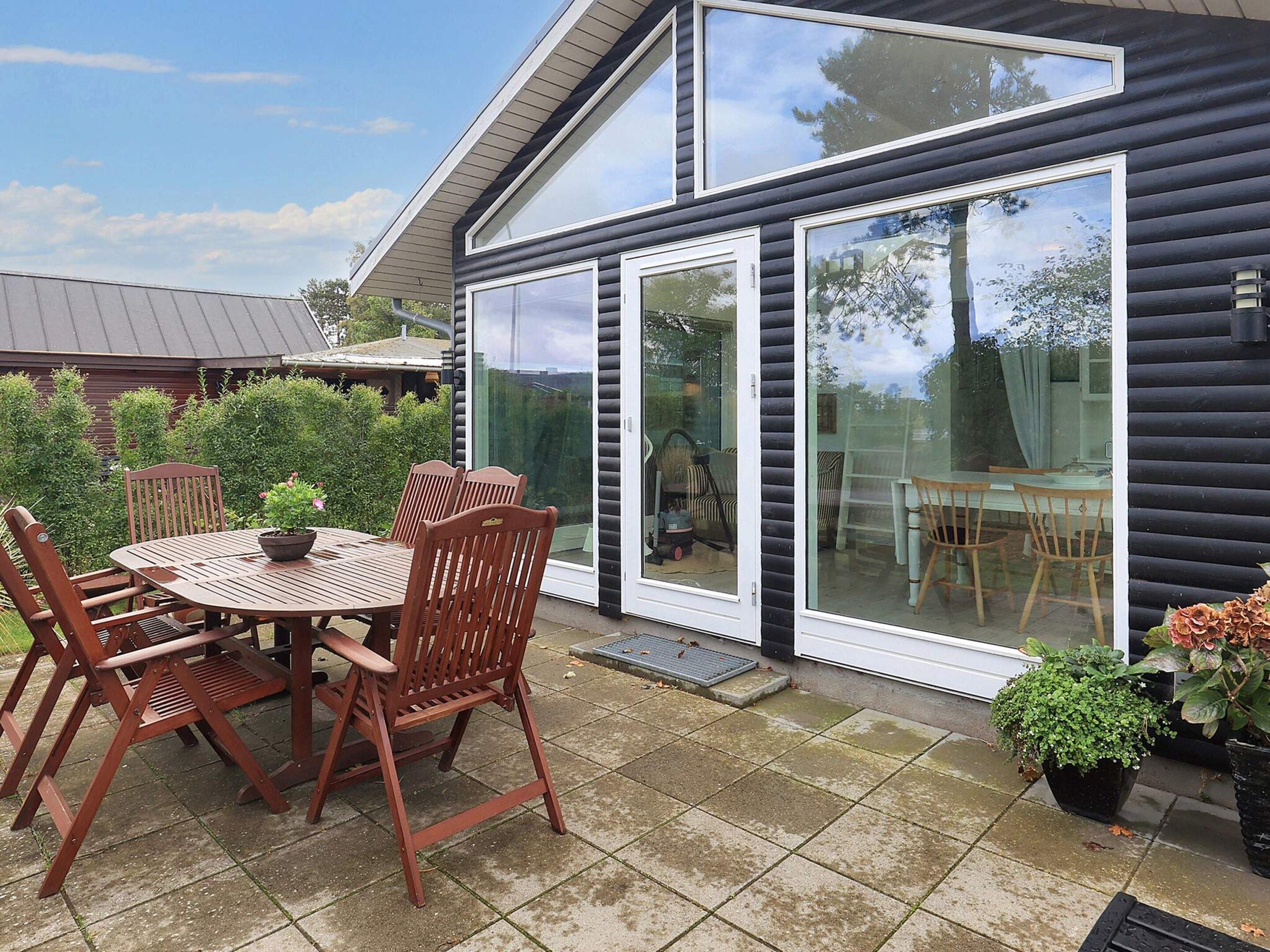 A patio with a table and chairs, a sliding glass door, and a view of the surrounding greenery.