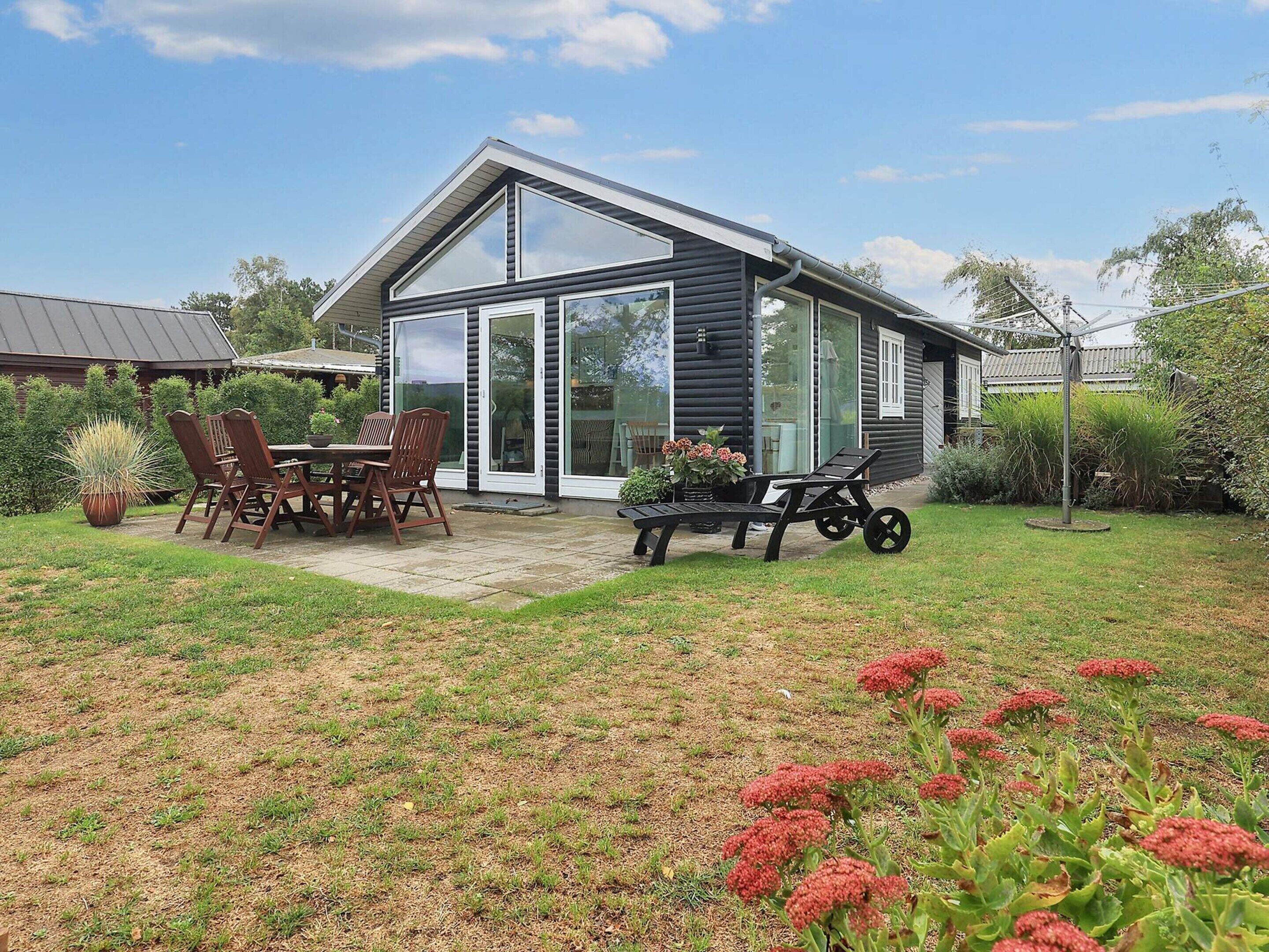 Une maison moderne dotée d’un patio, d’un ensemble de mobilier de salle à manger et d’un jardin.