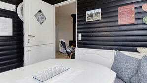 Una habitación con cama, puerta y techo blancos, y paredes negras. Hay una lámpara en el techo y un cuadro en la pared.