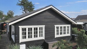 A log cabin with two white-framed windows, a small porch, and a sign indicating the number 15. - 4 Person Holiday Home in Karrebaeksminde (Karrebæksminde)