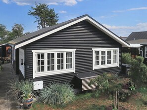 Une cabane en rondins avec deux fenêtres à cadre blanc, un petit porche et une enseigne indiquant le numéro 15.