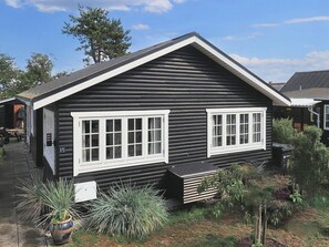 A log cabin with two white-framed windows, a small porch, and a sign indicating the number 15. - 4 Person Holiday Home in Karrebaeksminde (Karrebæksminde)
