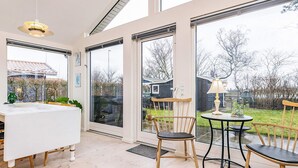 Un interior moderno con comedor, ventanas amplias y vista al jardín trasero.