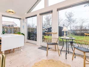 Un intérieur moderne avec un coin repas, de grandes fenêtres et une vue sur le jardin arrière.