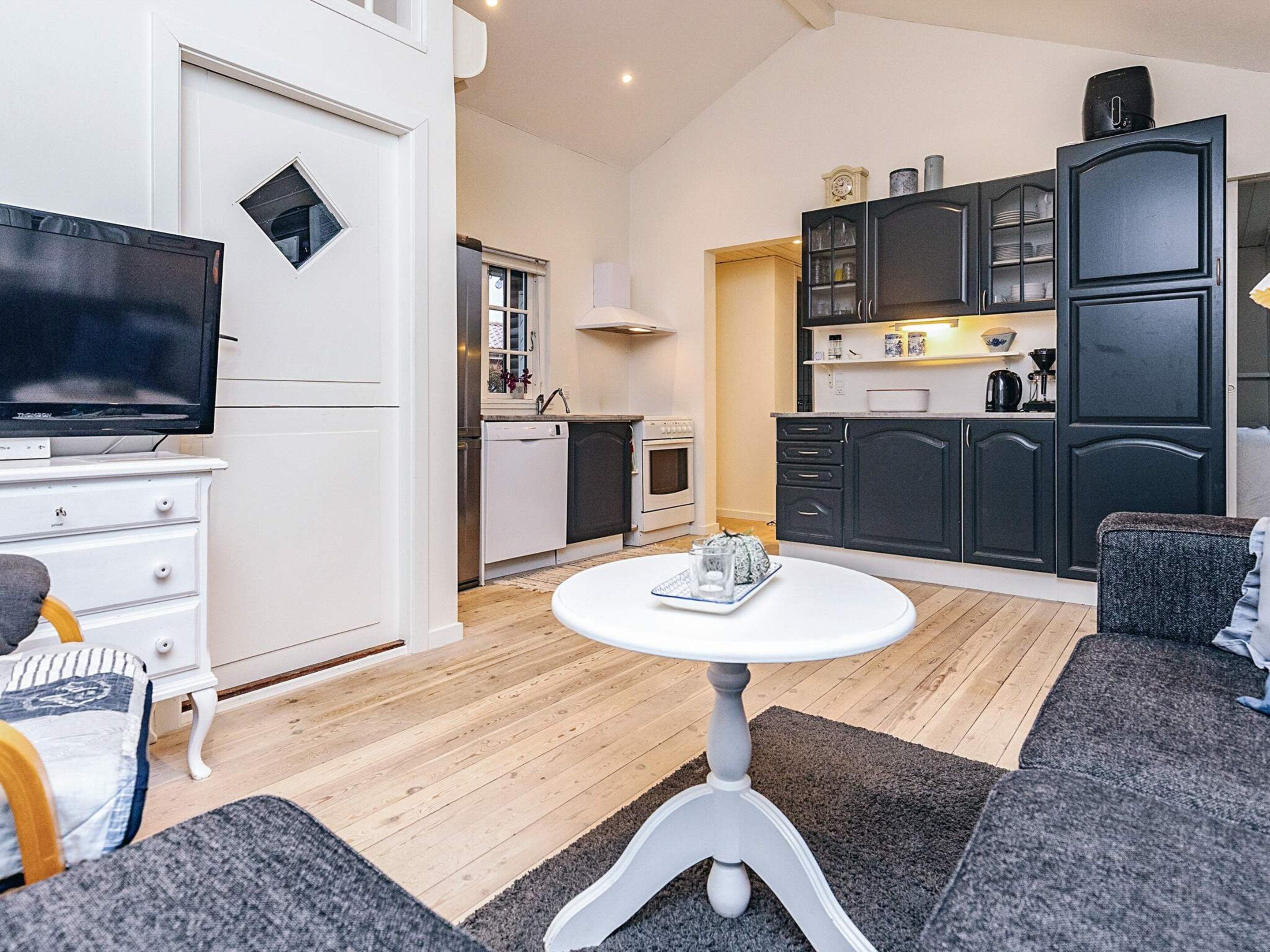 A compact living space with a television, kitchenette, and seating area.