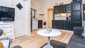 A compact living space with a television, kitchenette, and seating area.