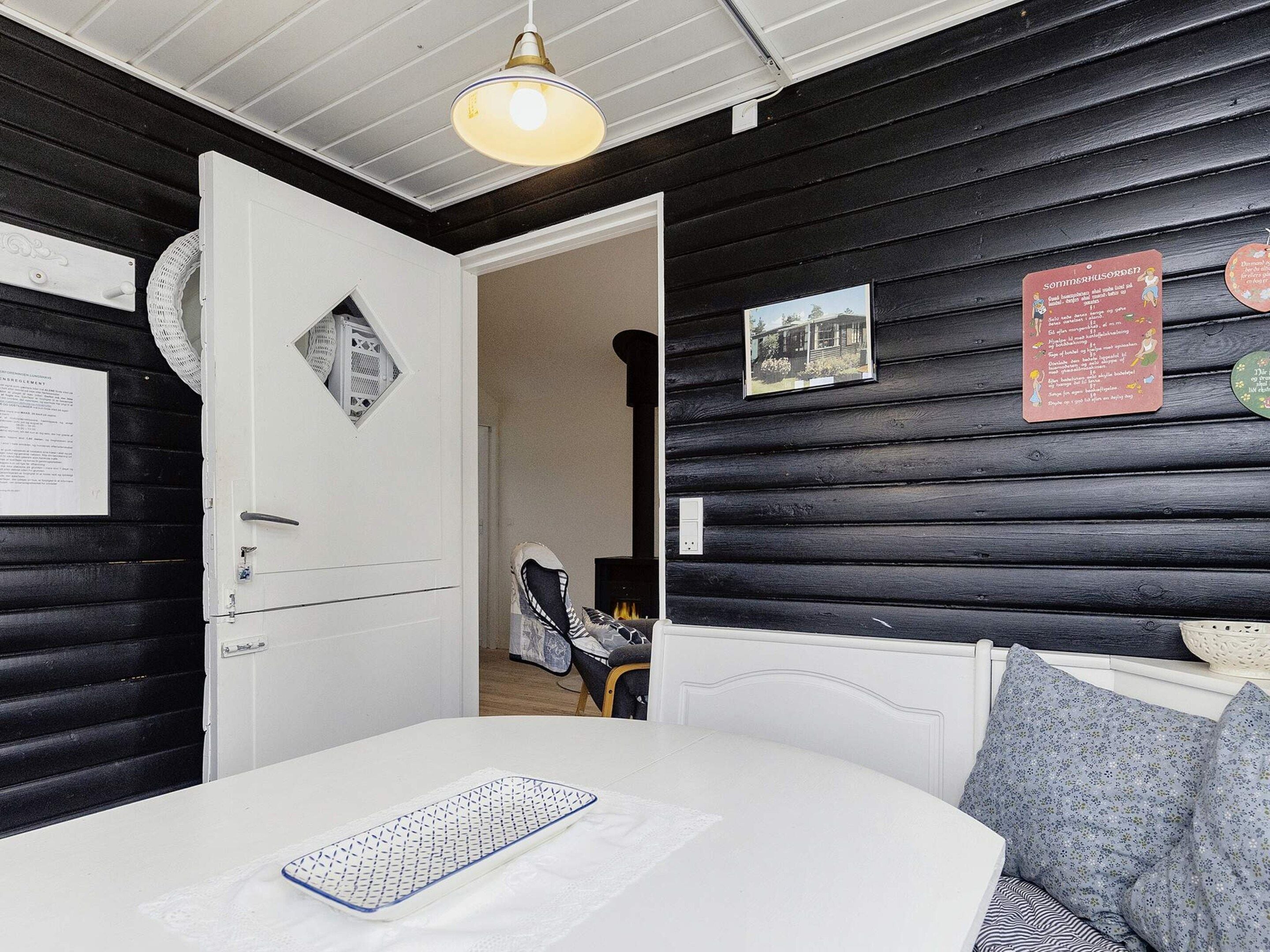 A room with a bed, a white door, a wall-mounted light fixture, and a framed picture.