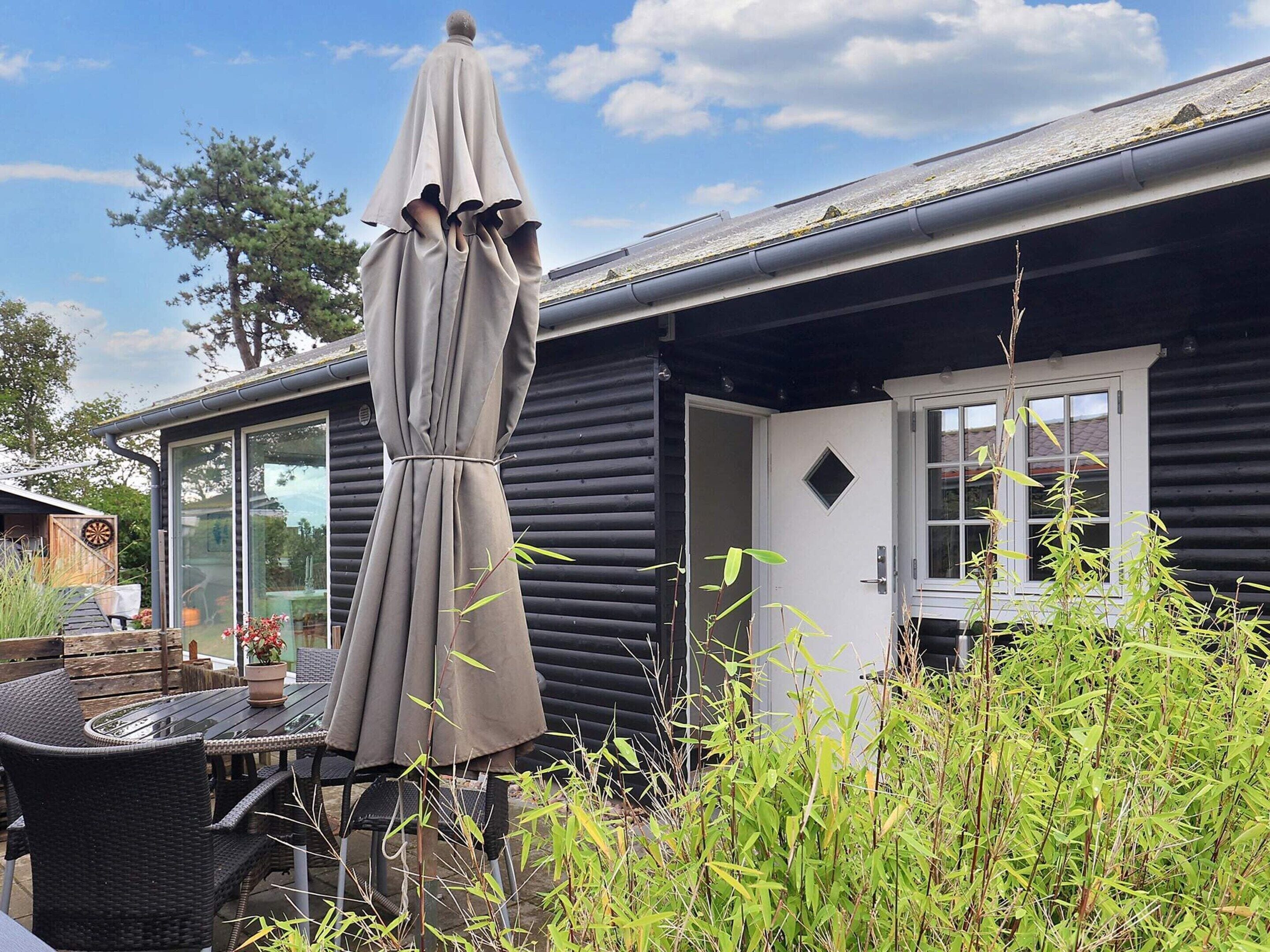 A wooden cabin with a covered outdoor seating area and a door.