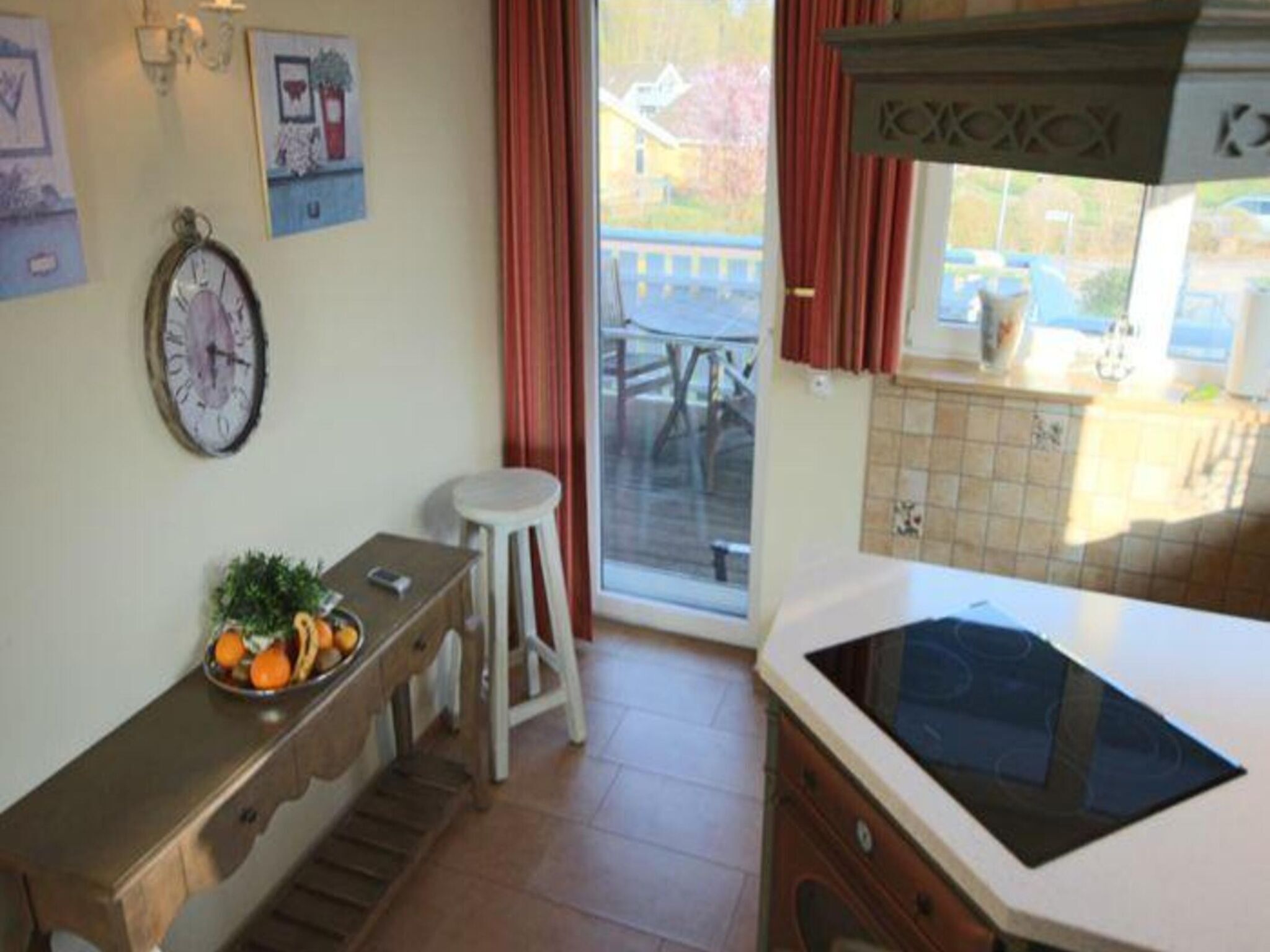 Una cocina con un banco de madera, un reloj y una ventana con cortinas.