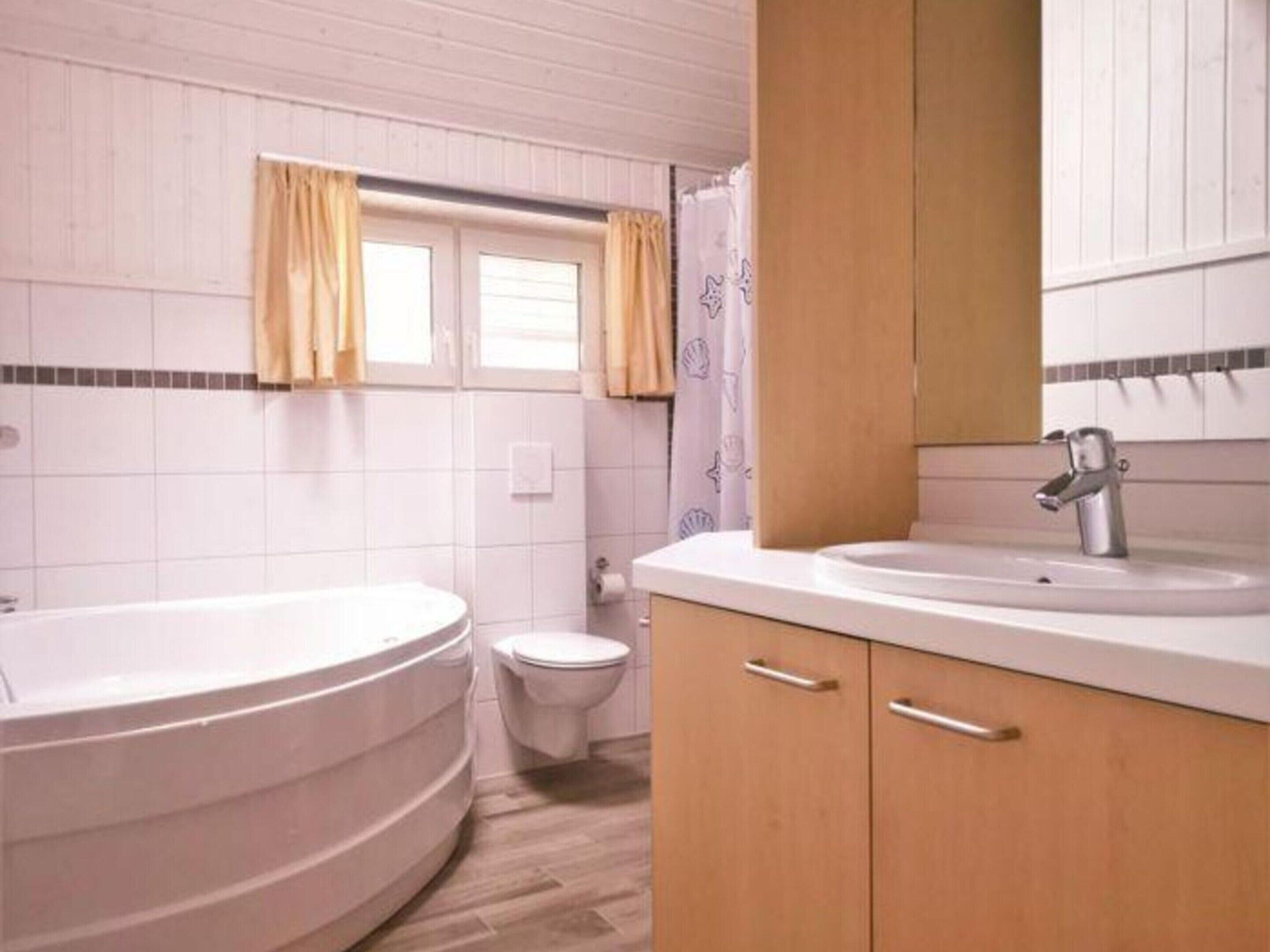 Een badkamer met een bad, toilet en wastafel.