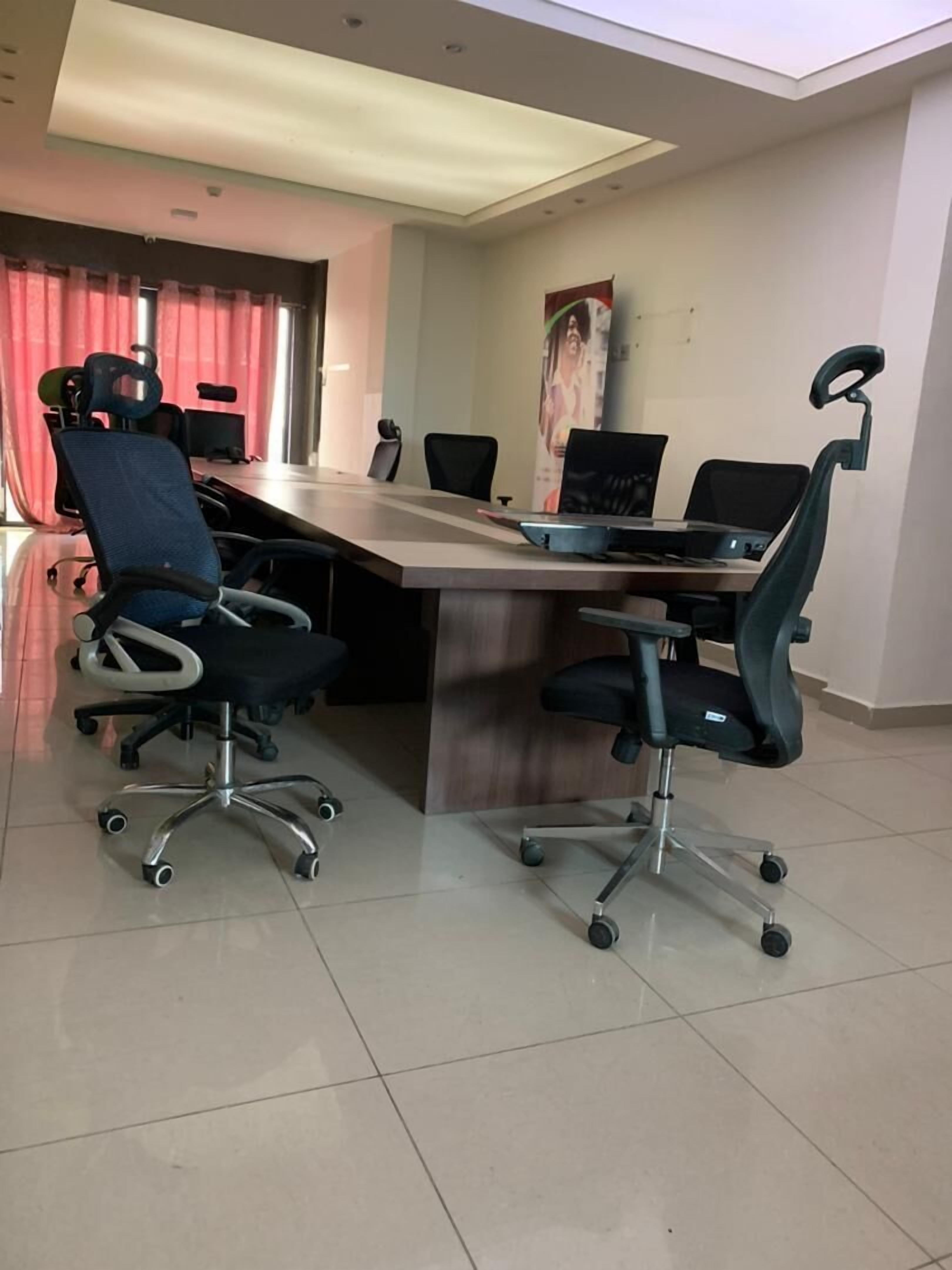 A conference room with a long table, four office chairs, and two laptops.