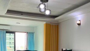 A living room with a teal sofa, a coffee table, a TV stand, and a patterned rug. - Riyad City (Douala)