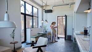 Una cocina moderna con un ventanal grande, un comedor con mesa y sillas, y un cubo de basura a la vista.