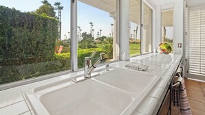 Een moderne keuken met een ruime gootsteen en uitzicht op een verzorgde tuin.