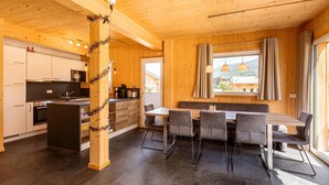 Une cuisine moderne avec des meubles en bois, un coin repas comprenant une table et des chaises, et une grande fenêtre agrémentée de rideaux.