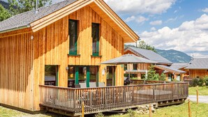Un chalet en bois doté d’un balcon et d’un espace extérieur aménagé pour s’asseoir.