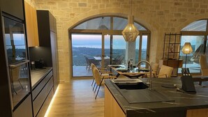 Une cuisine moderne dotée d’un grand îlot central, d’un plancher en bois et offrant une vue sur un paysage montagneux grâce à de grandes fenêtres.
