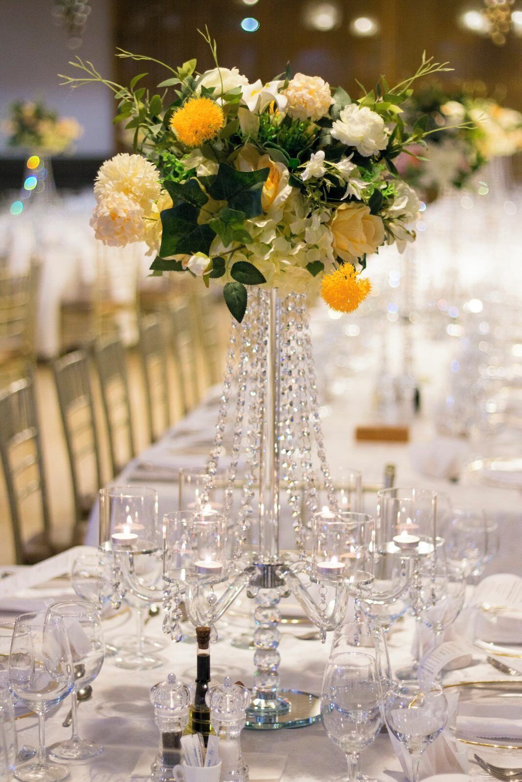 A long banquet table with crystal chandeliers and floral centerpieces.