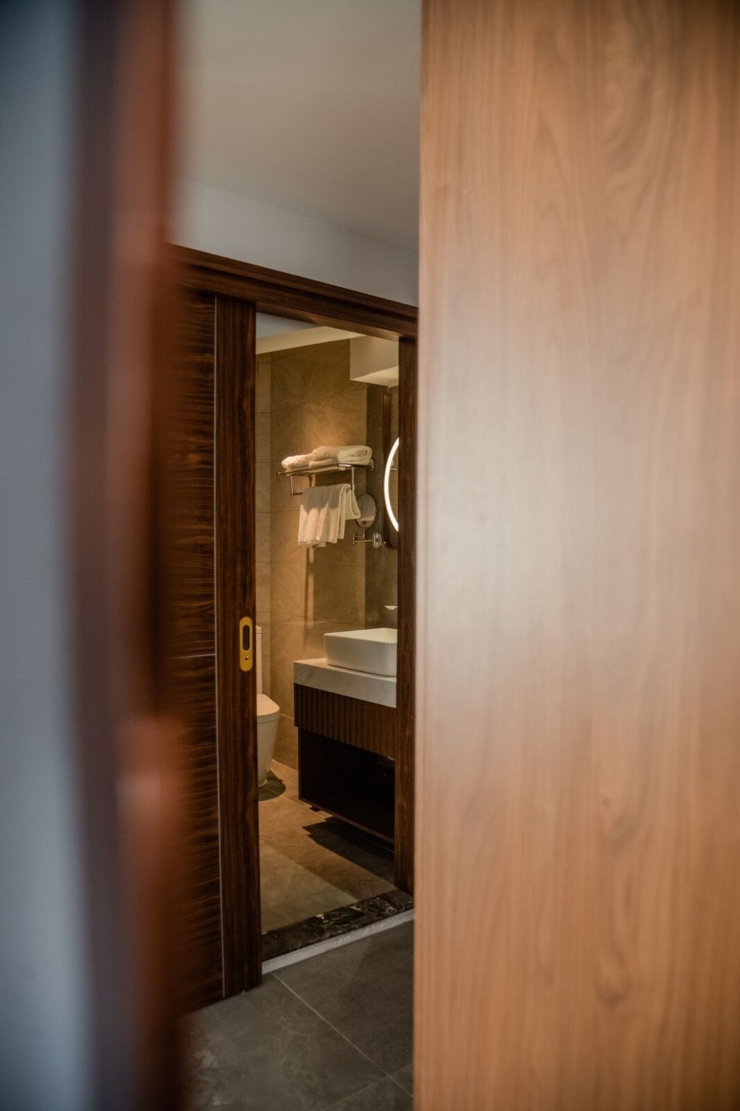 Un bagno moderno con porta in legno, box doccia in vetro e lavandino bianco.
