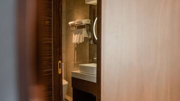 Un bagno moderno con porta in legno, box doccia in vetro e lavandino bianco.