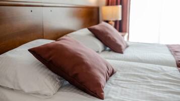A hotel room with two beds, each with white bedding and brown pillows.