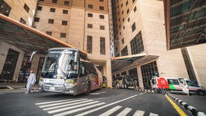Un edificio de varios pisos con un autobús grande estacionado frente a él.